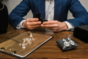 Cropped view of jewelry appraiser holding box with jewelry ring near jewelry and tools on table on